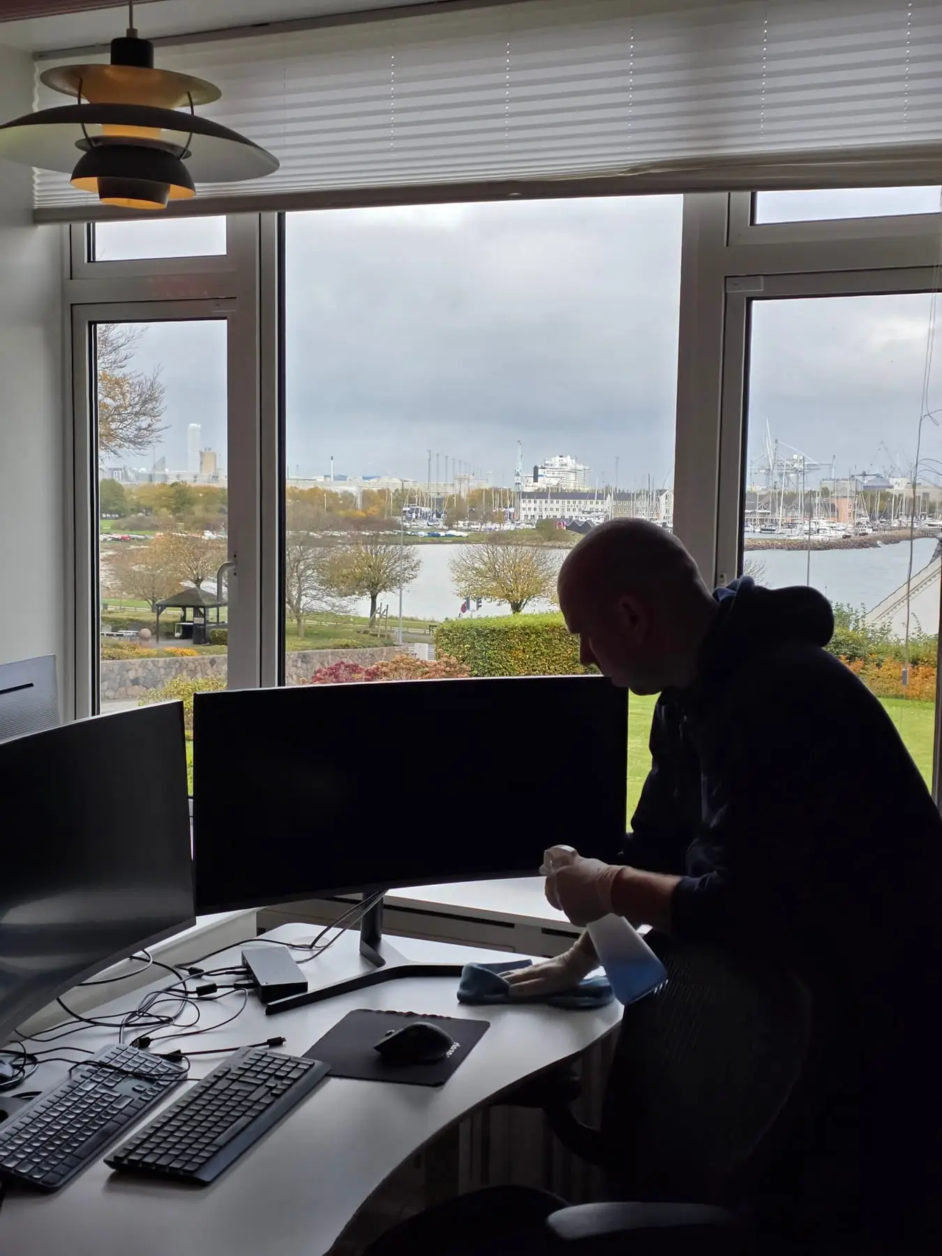 Mand rengør skrivebord ved vindue med havudsigt
