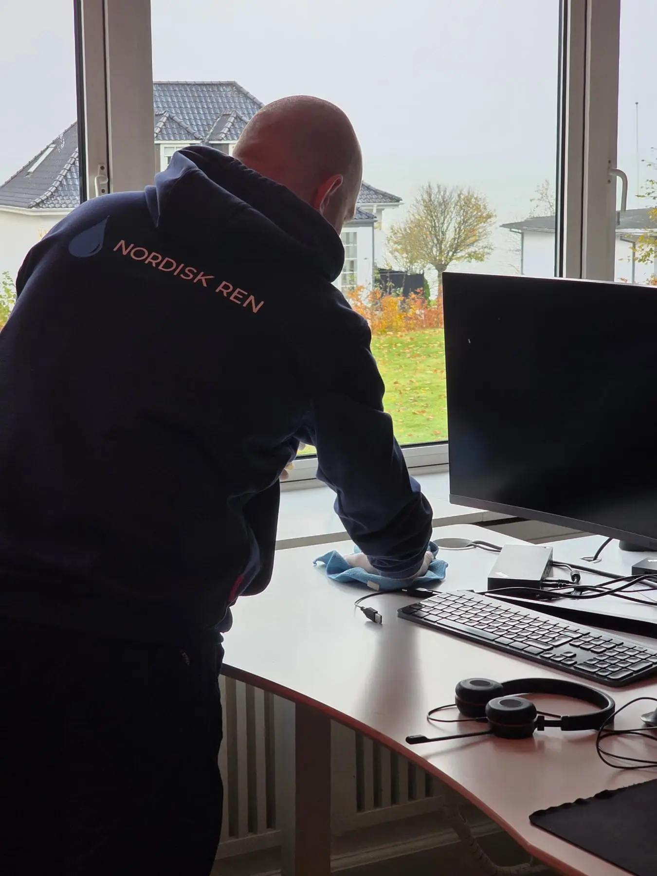 Mand rengør skrivebord ved kontorvindue