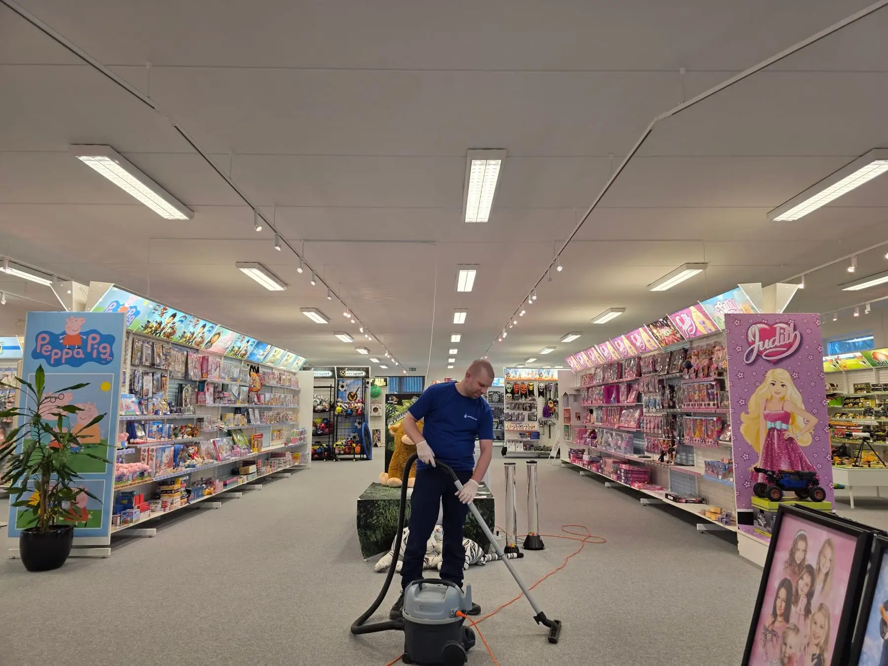 Mand støvsuger i farverig legetøjsbutik