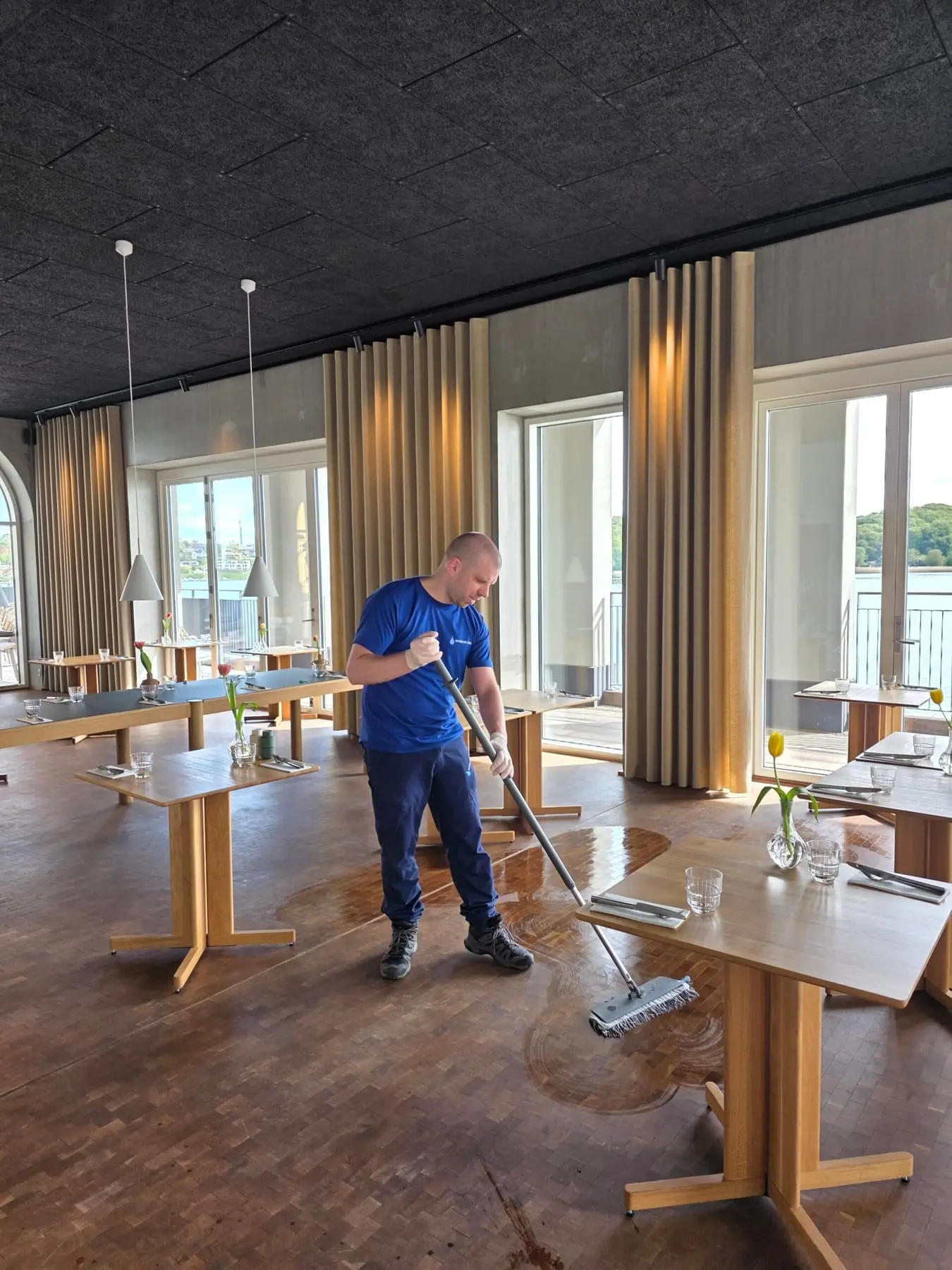 Mand vasker gulv i moderne restaurant