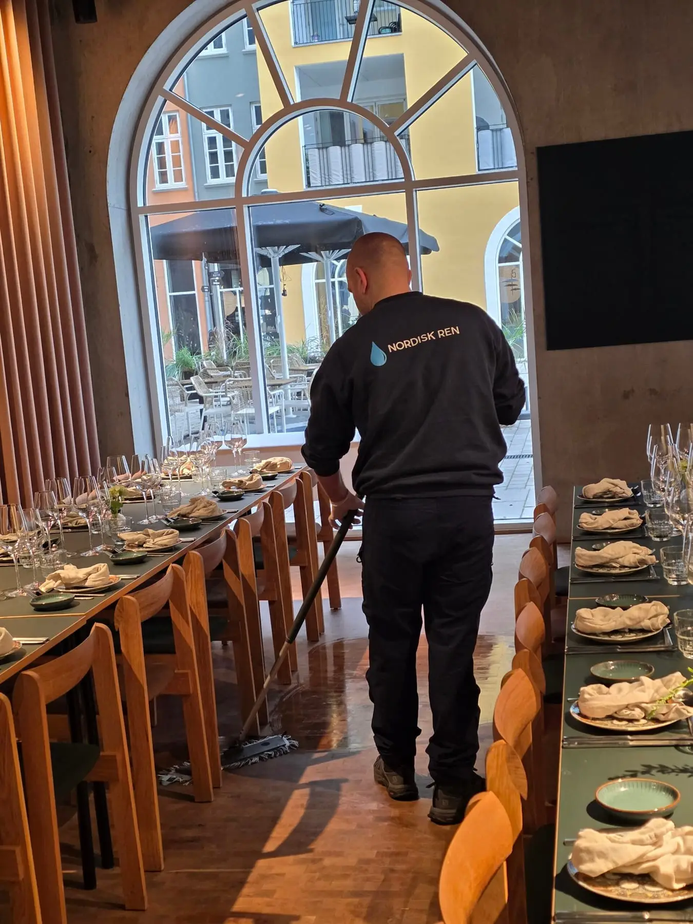 Rengøringsmedarbejder mopper gulv i restaurant
