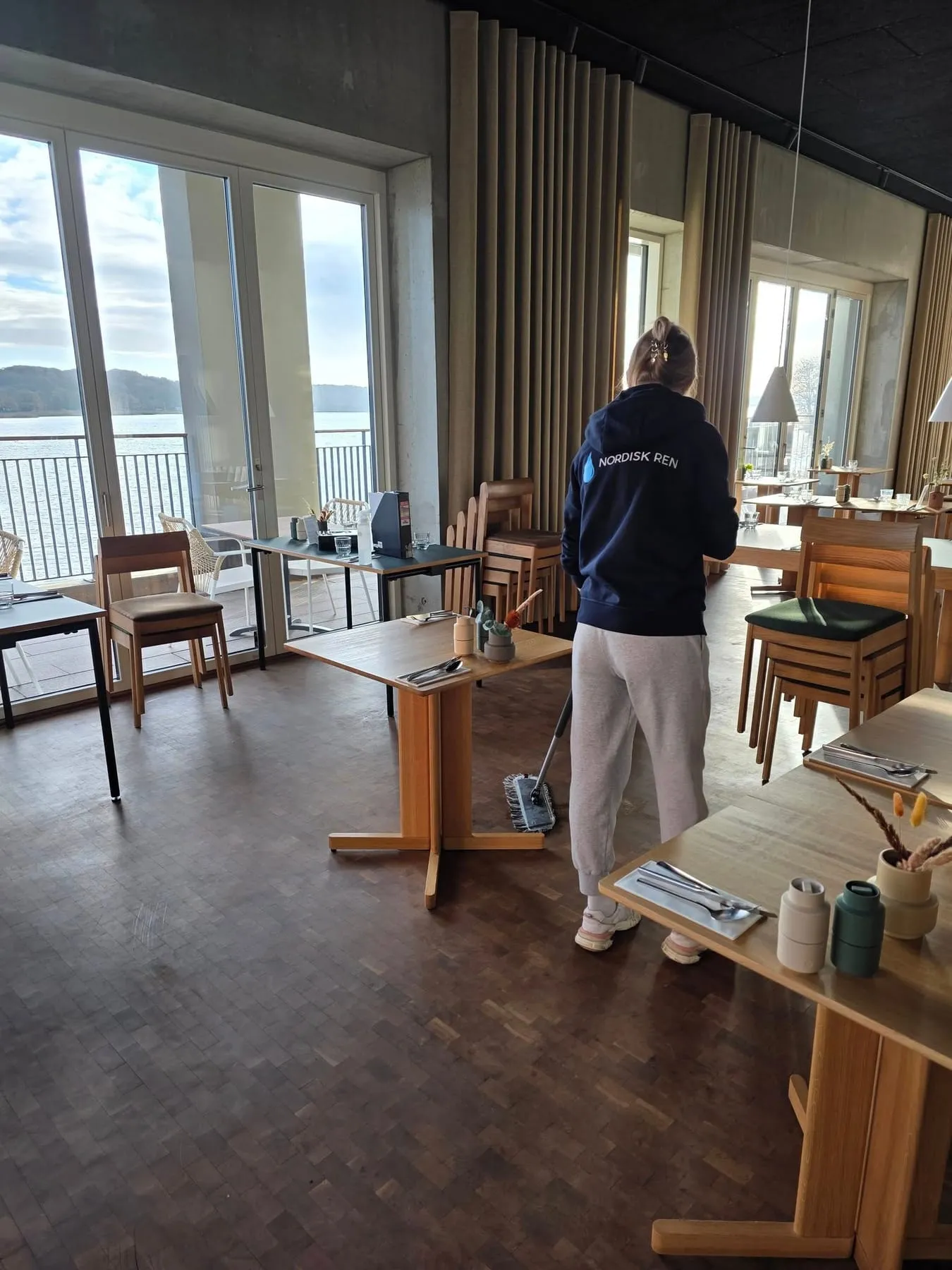 Rengøringsmedarbejder vasker gulv i lys restaurant